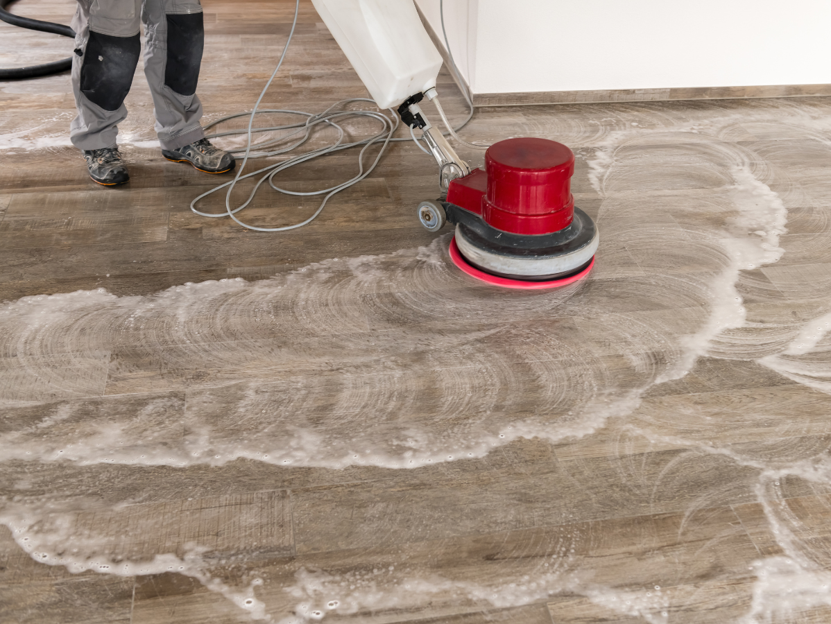 Person using a floor buffer to scrub a floor with soapy water.