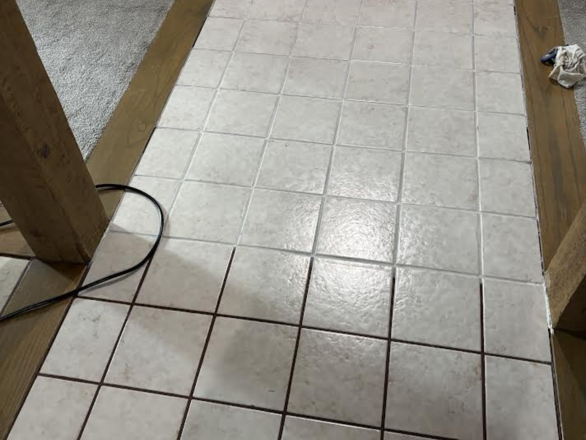 White tile floor, rectangular tiles, with black grout, wood framing.