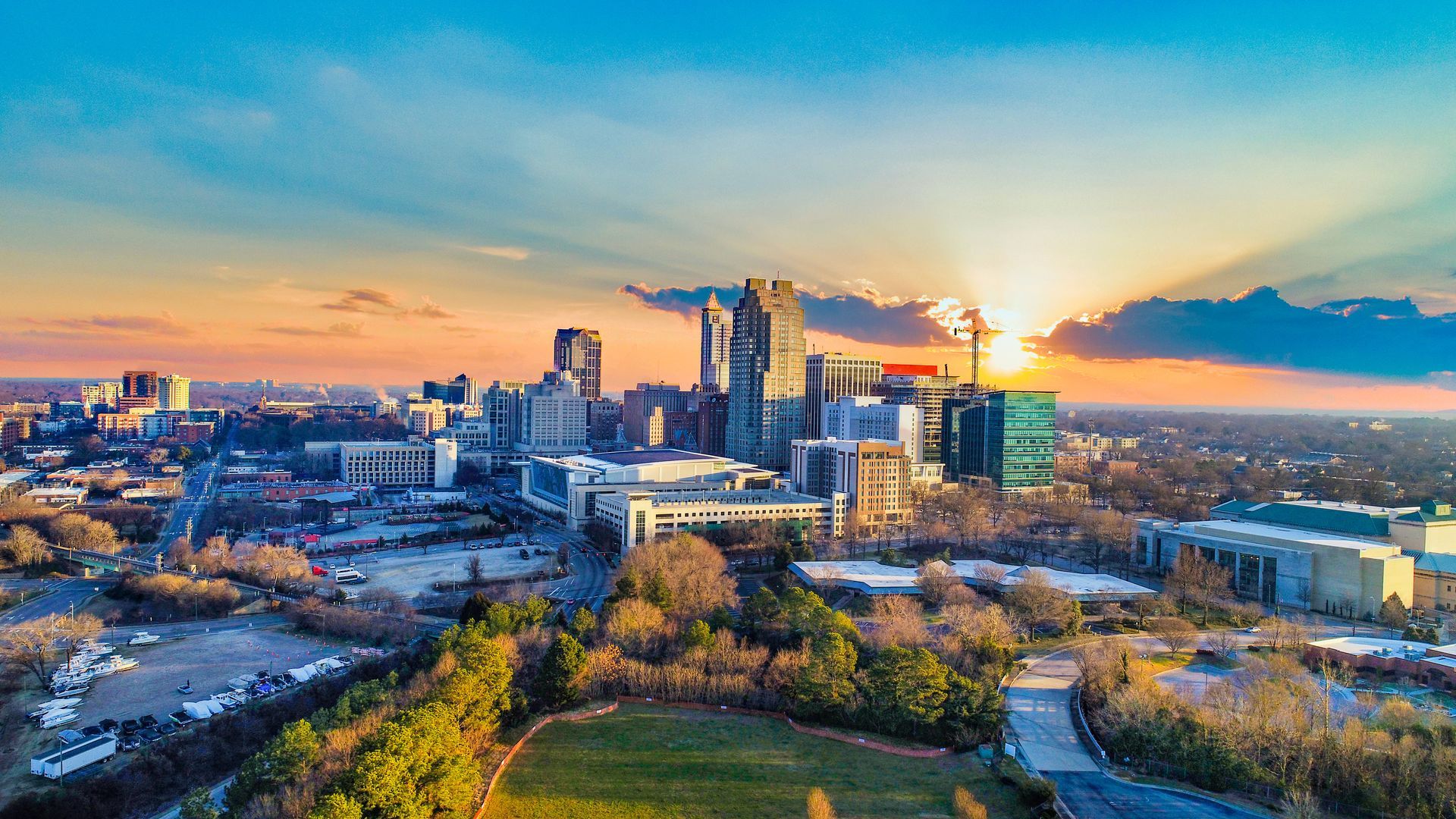 Nighttime cityscape of Raleigh, North Carolina, with illuminated buildings against a twilight sky.