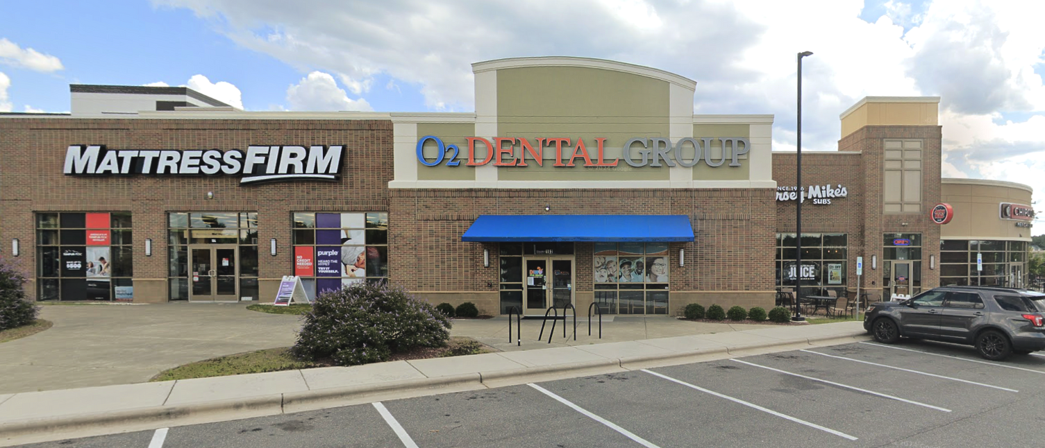 A shopping center featuring Mattress Firm, Dental Care of Georgia, and other businesses with cars parked in the front.