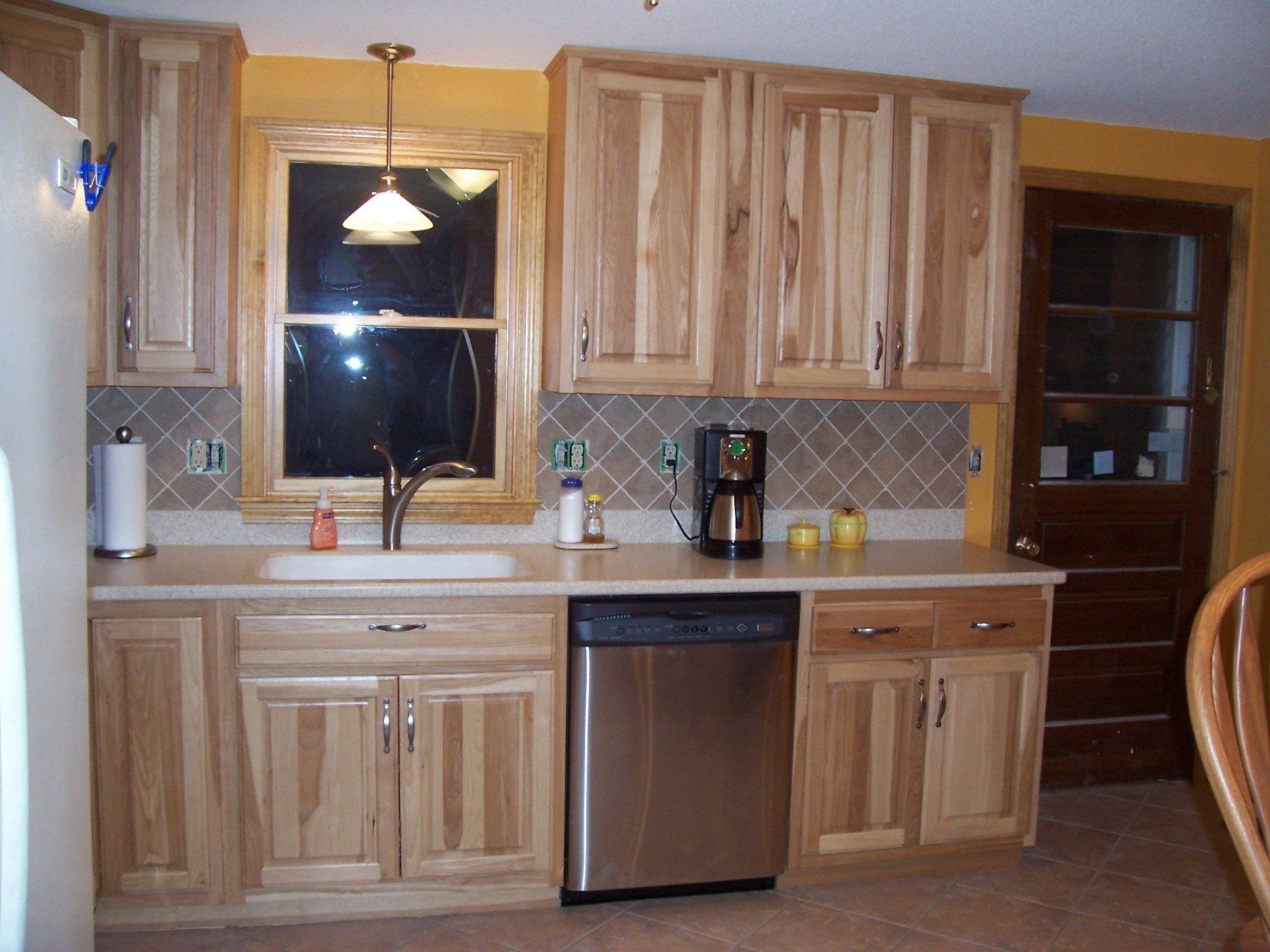 A kitchen with wooden cabinets and a stainless steel dishwasher