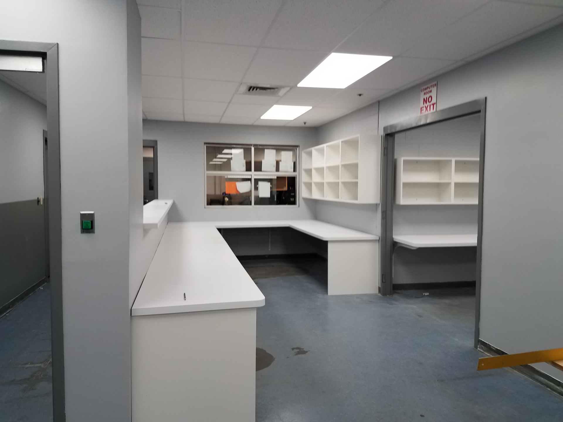 An empty room with a green exit sign on the wall