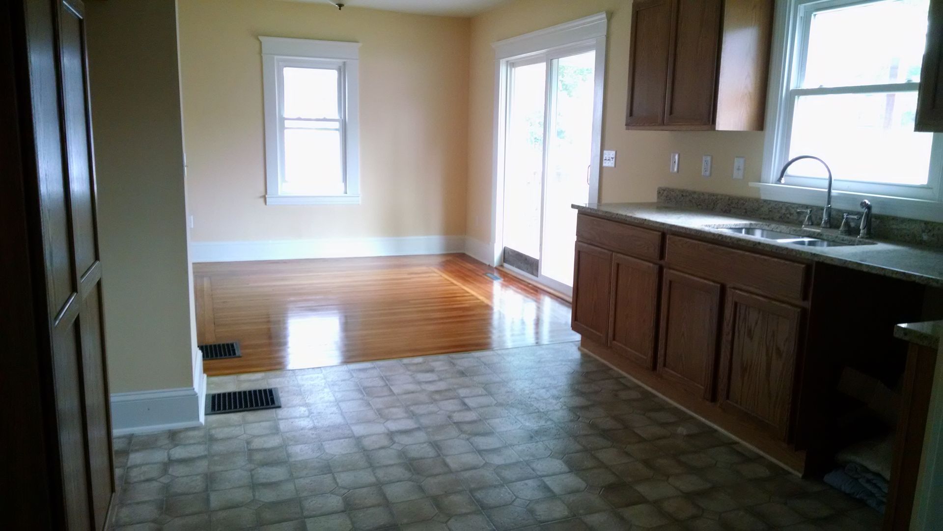 An empty kitchen with wooden cabinets and a sink.