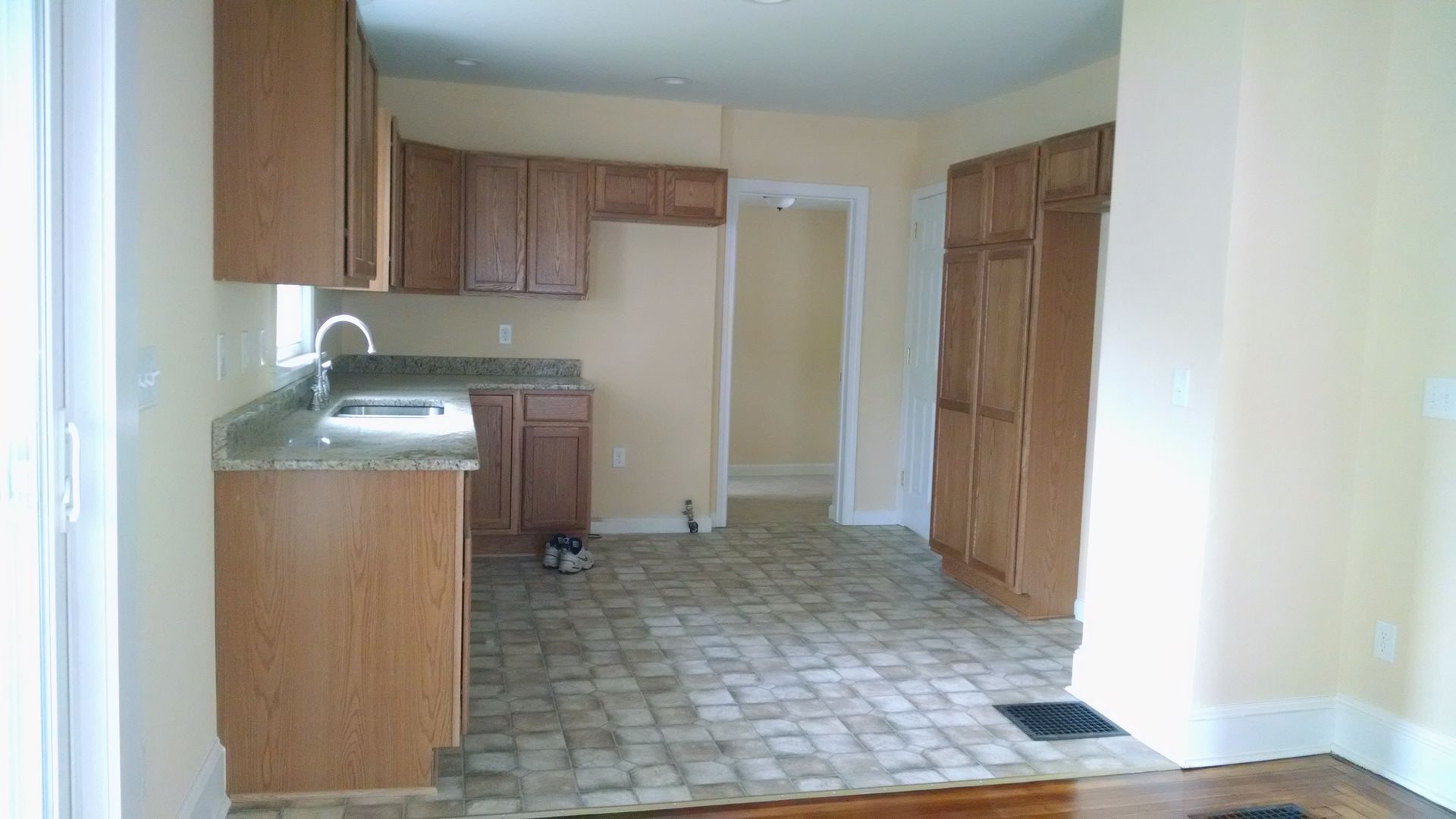 An empty kitchen with wooden cabinets and a tile floor.