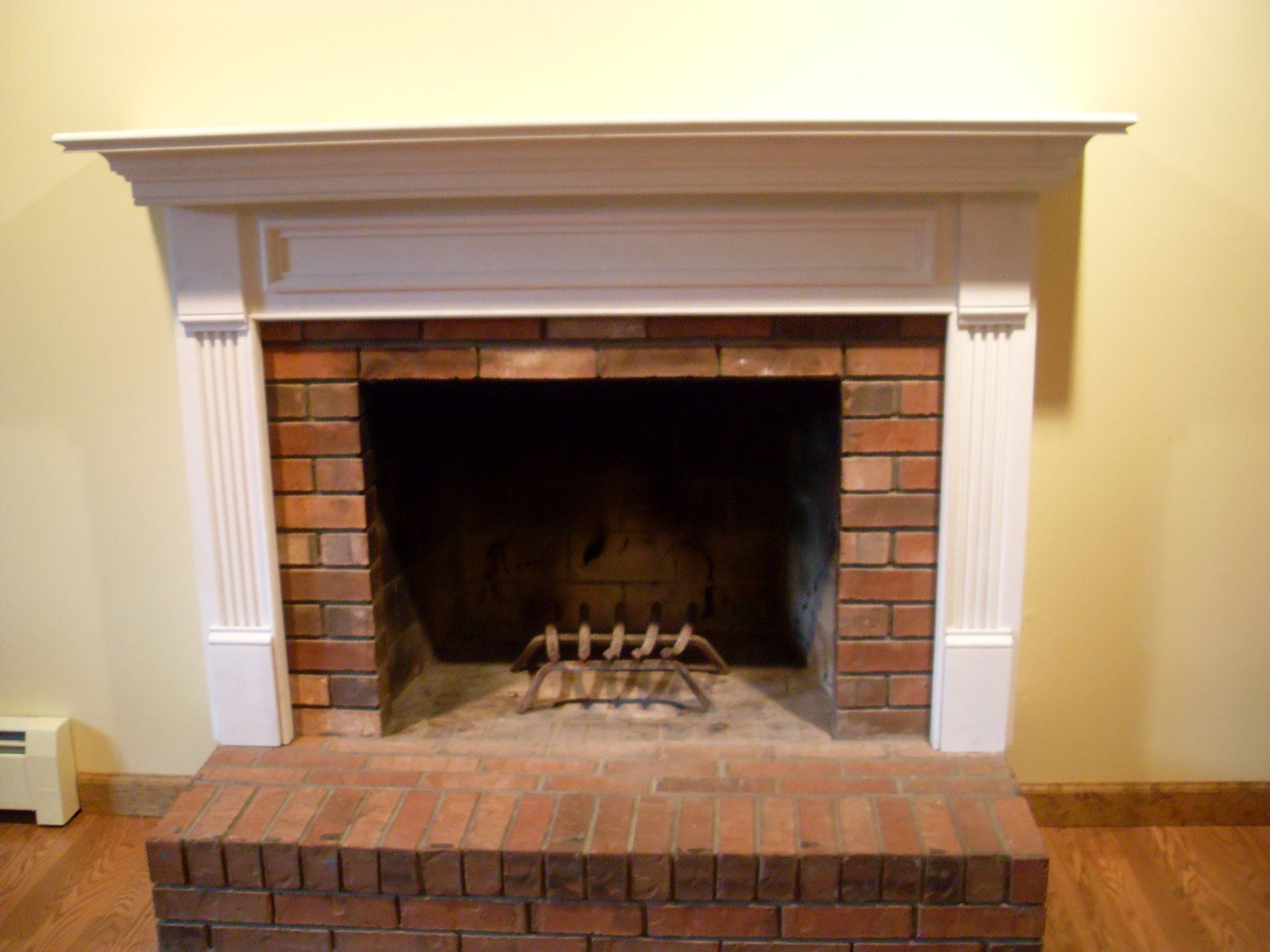 A brick fireplace with a white mantle in a living room