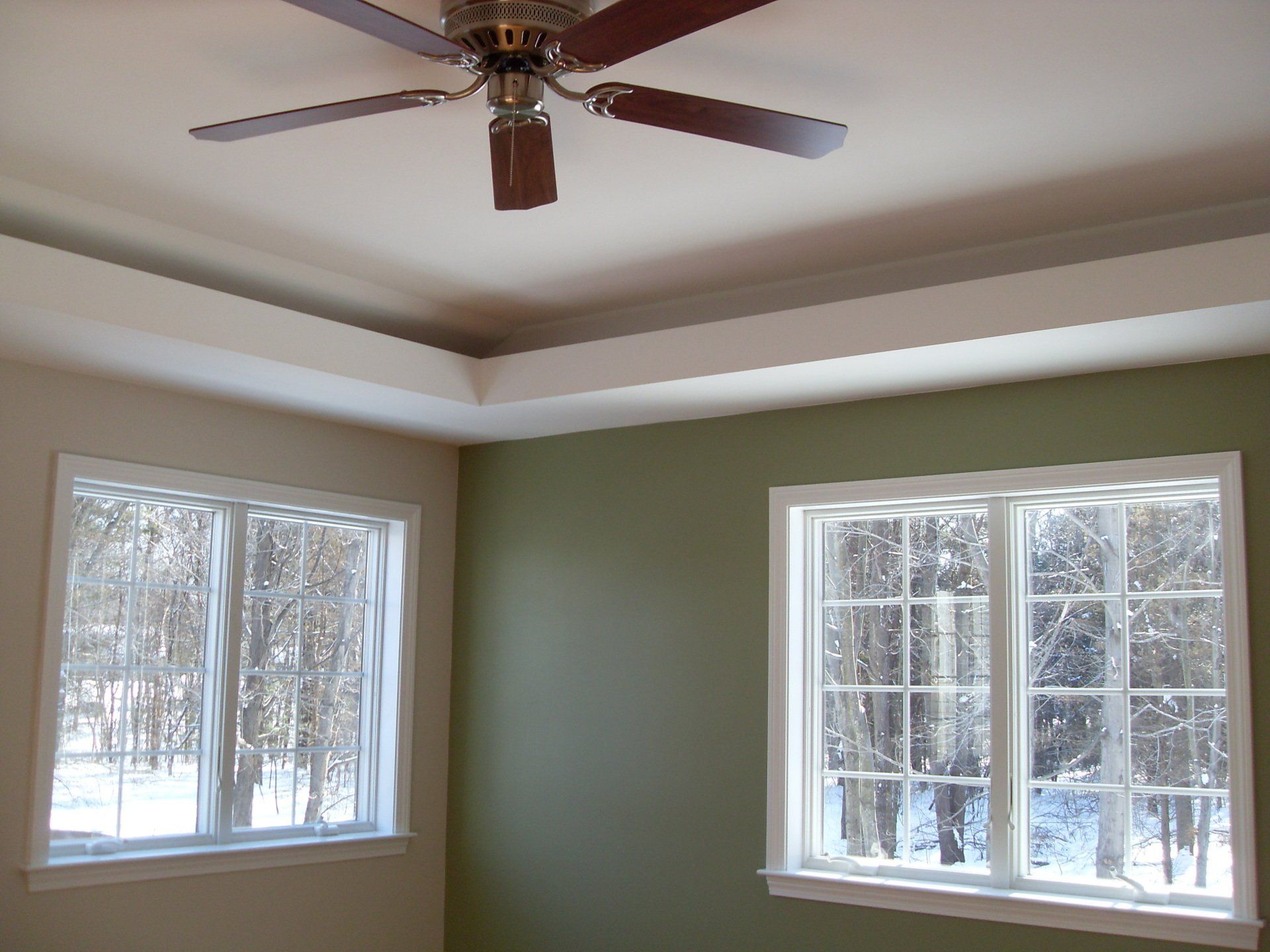 A room with two windows and a ceiling fan