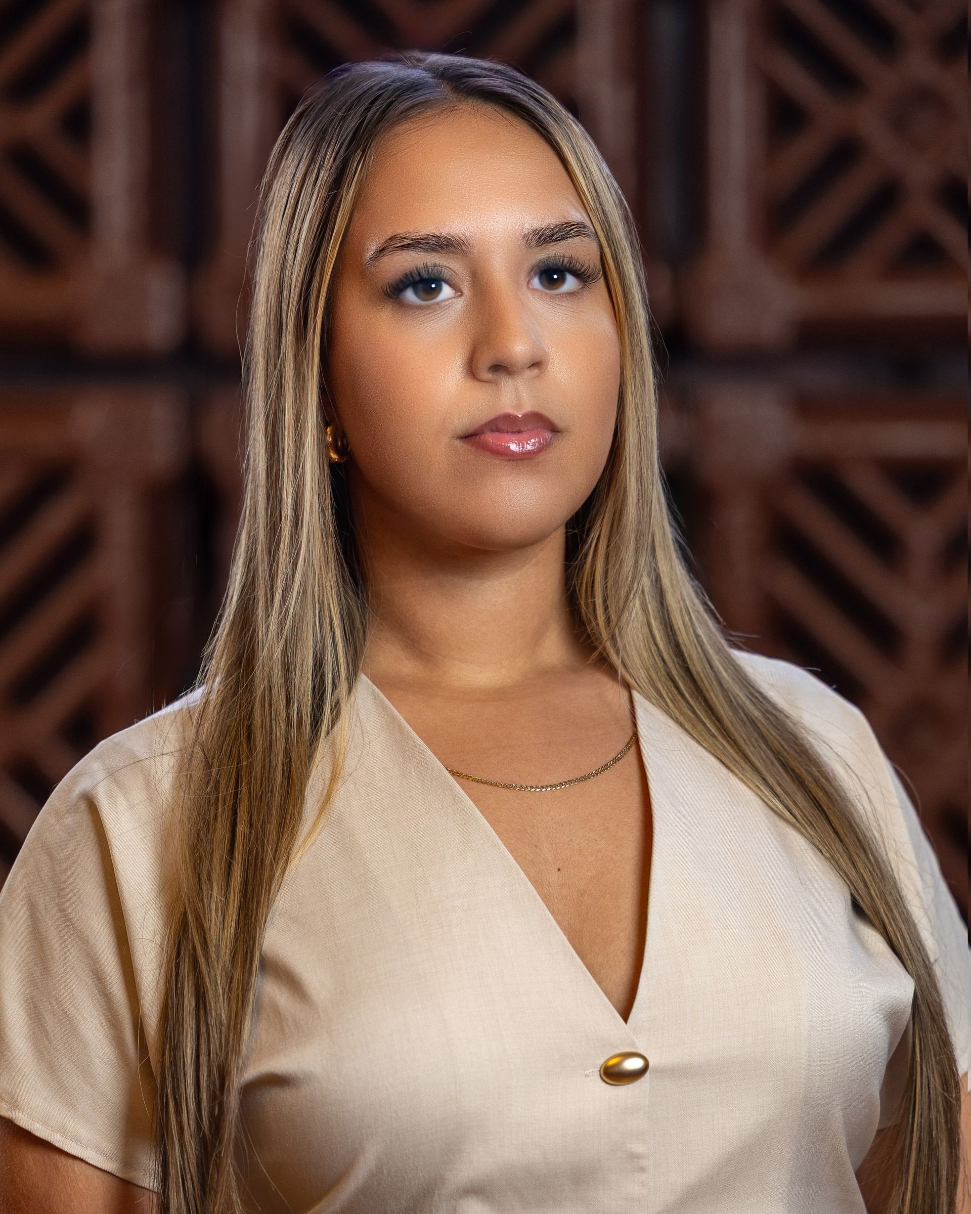 Woman with long blonde hair, wearing a beige top, looking at the camera.
