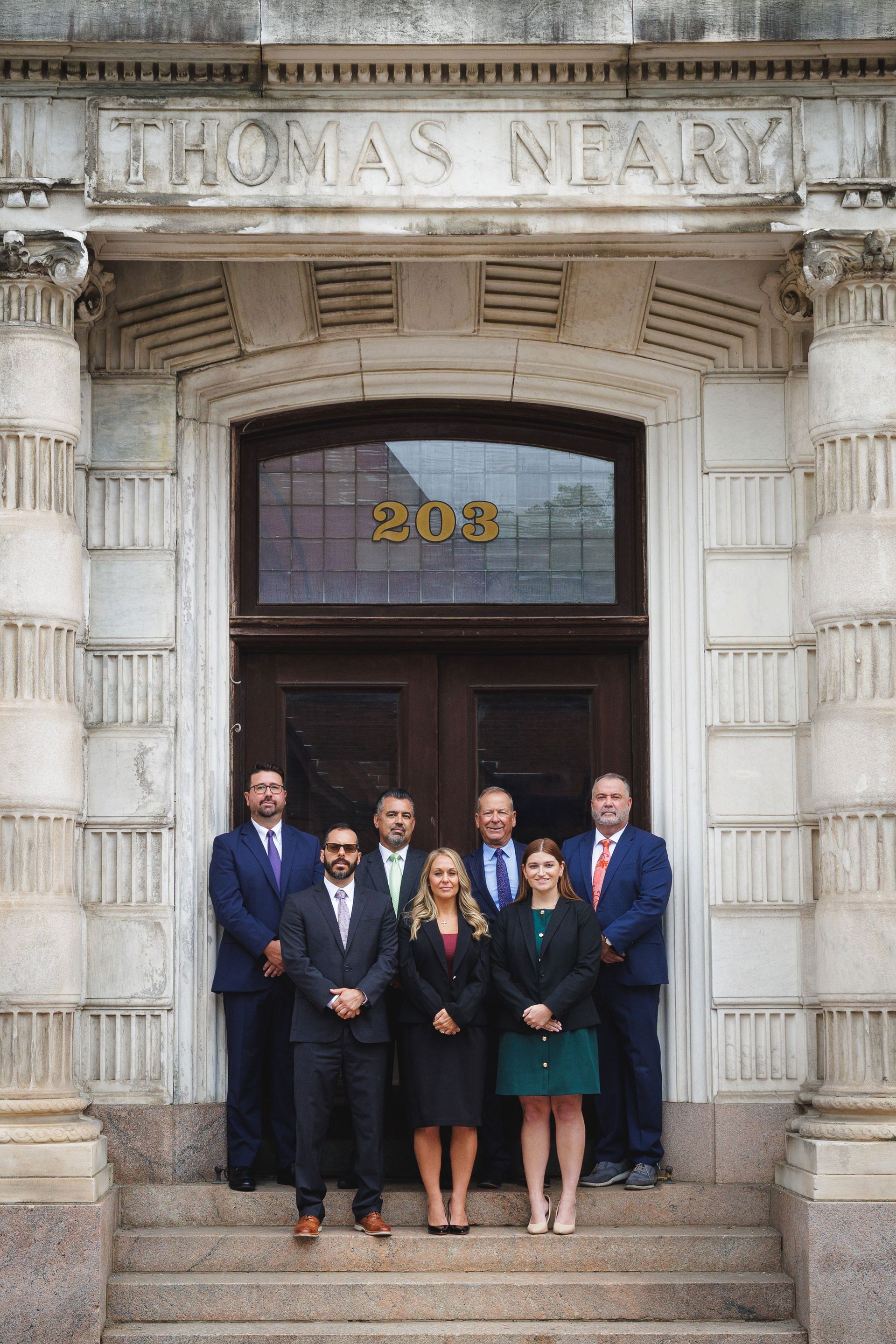 Group of professionals posing in front of a building with the name 