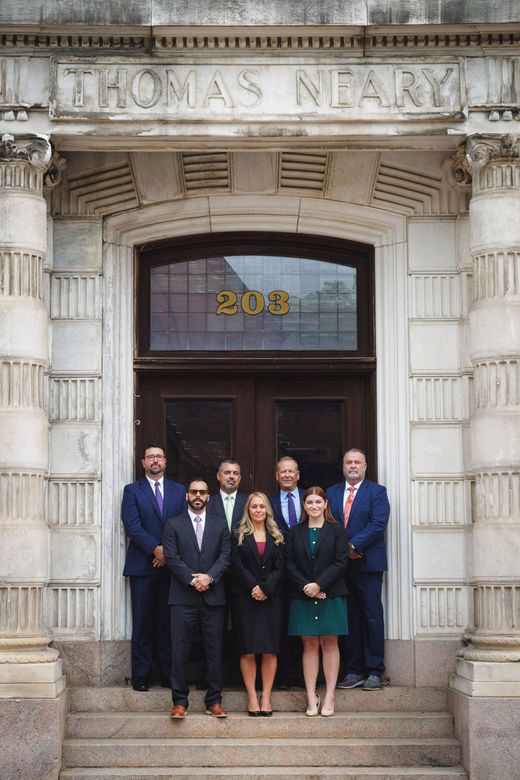 Group of people in business attire standing outside a building with the name