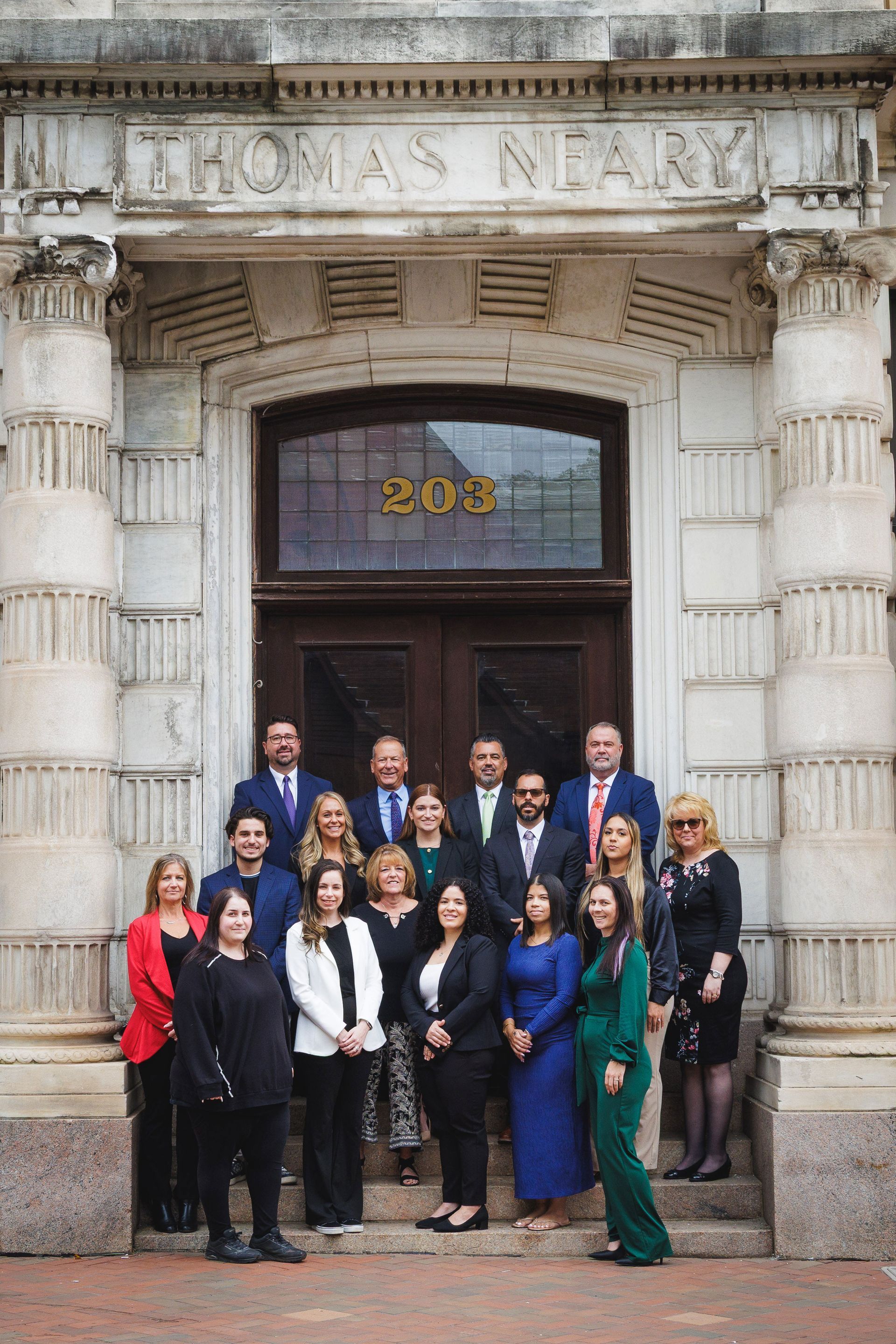 Group of people posing on the steps of a building with the name