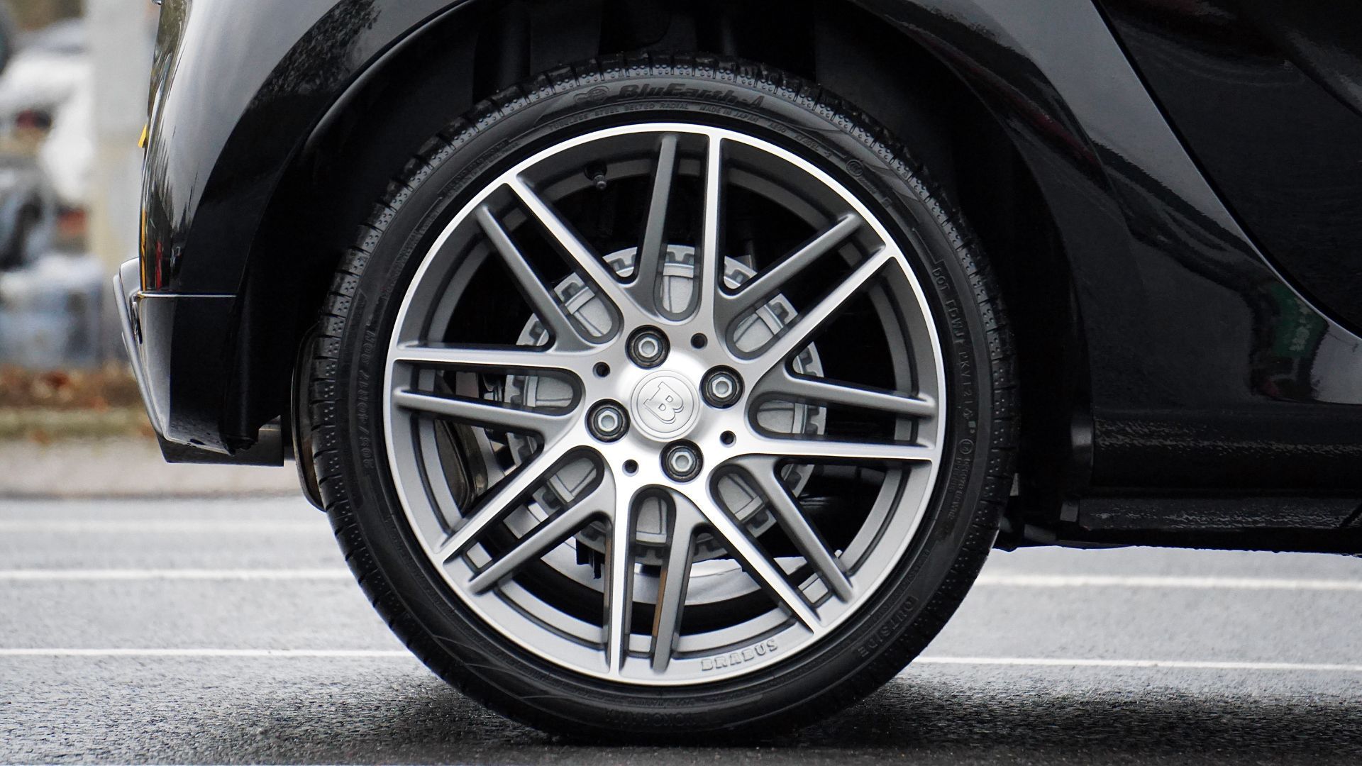 A close up of a car wheel on a wet road.