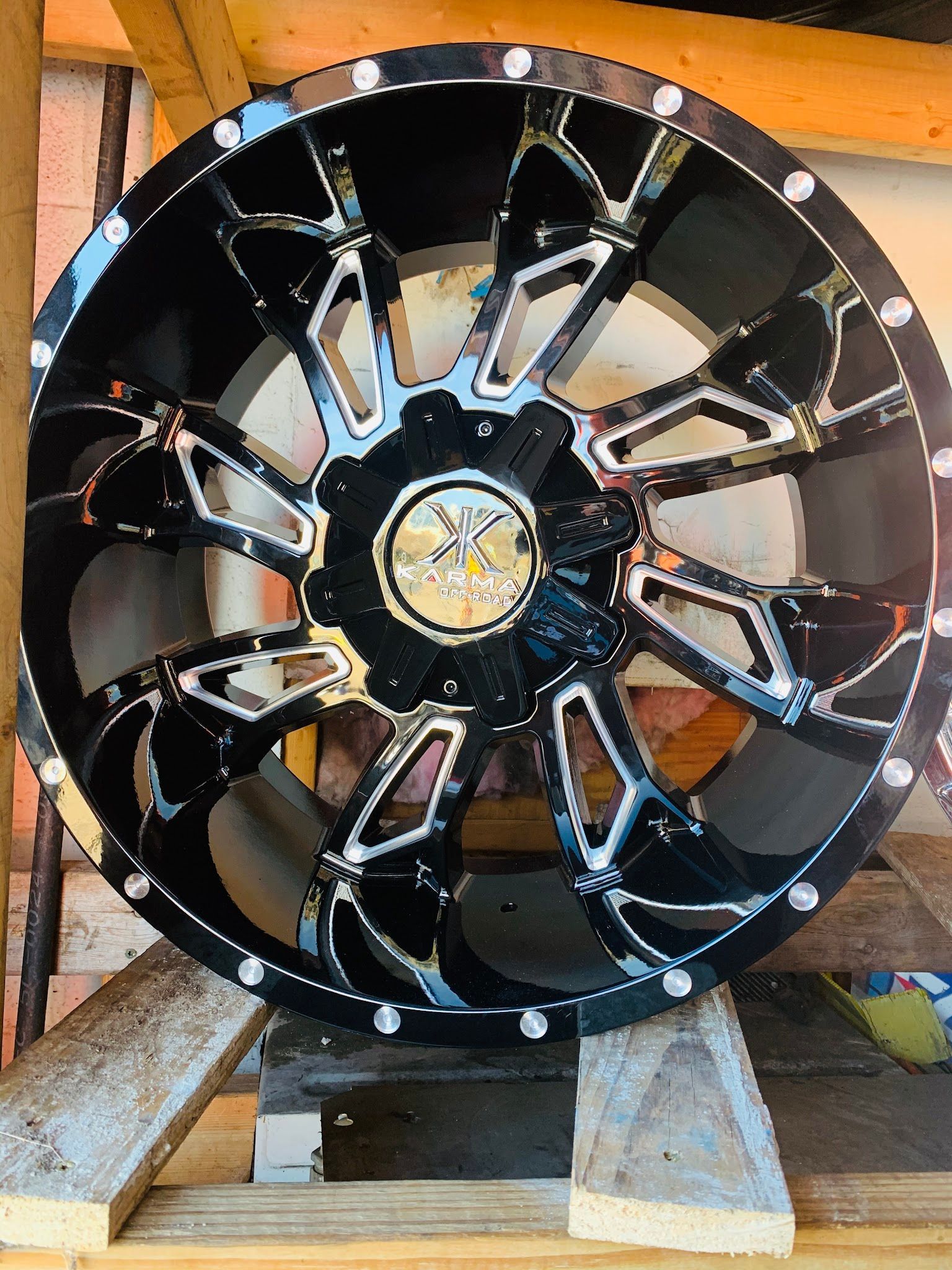 A black and silver wheel is sitting on top of a wooden pallet.