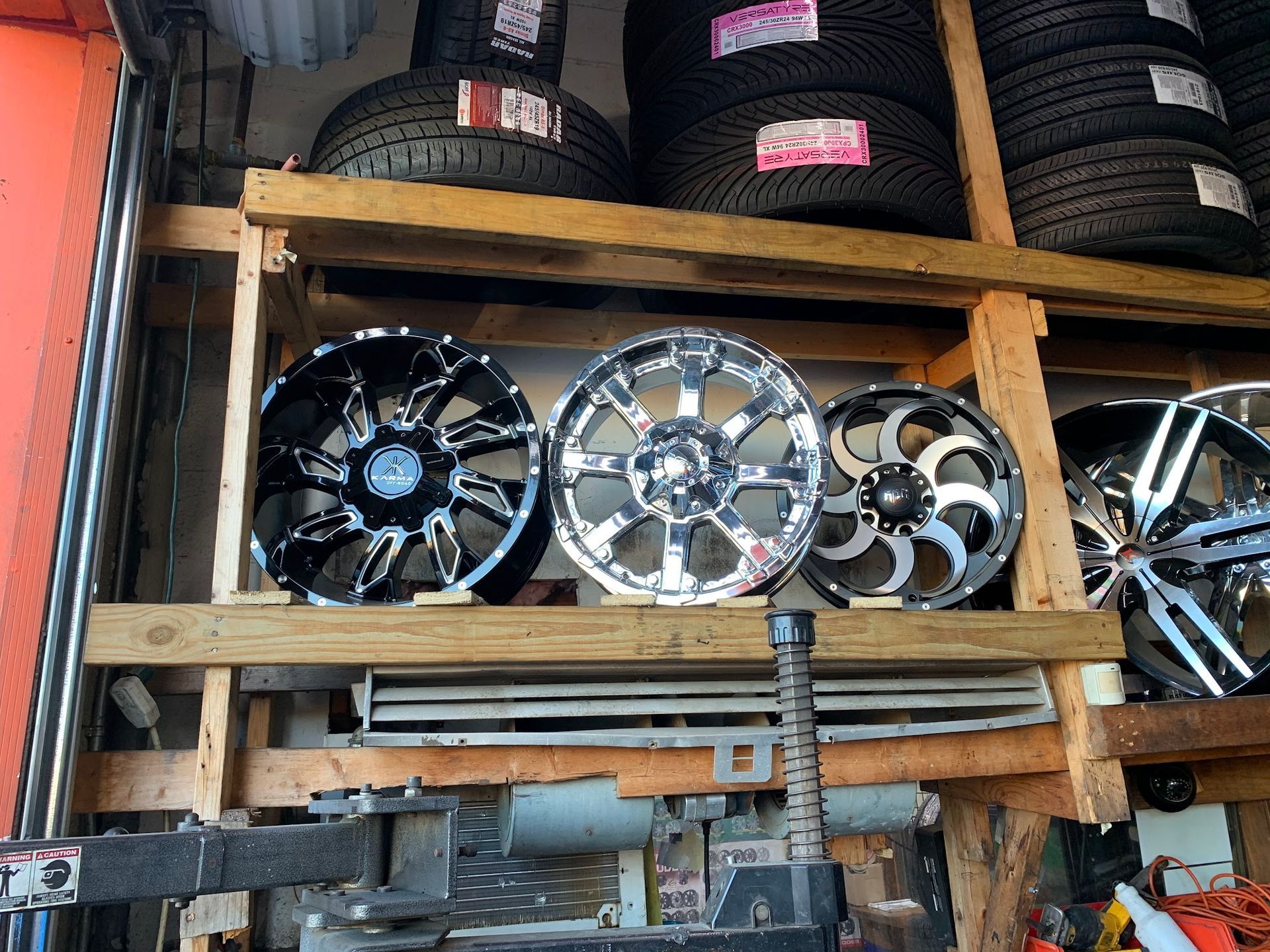 A display of wheels and tires on a wooden shelf.