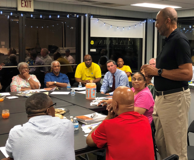 A town square with a small Eiffel Tower replica. Buildings on either side and a blue car in front.