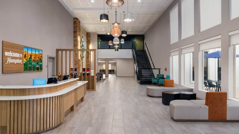 An artist 's impression of a hotel lobby with a reception desk and stairs.