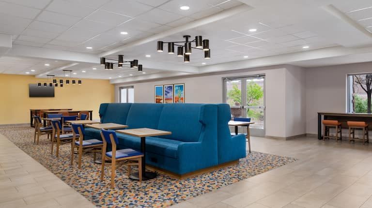 A hotel lobby with tables and chairs and a blue couch.