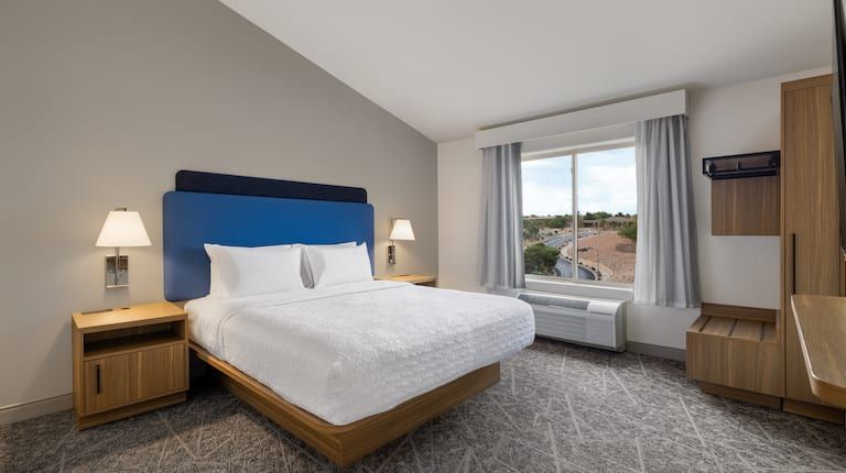 A hotel room with a king size bed and a large window.