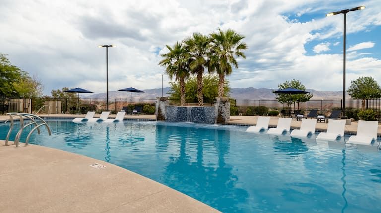 A large swimming pool with chairs and umbrellas around it.