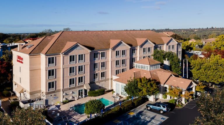 An aerial view of a large hotel with a pool in front of it