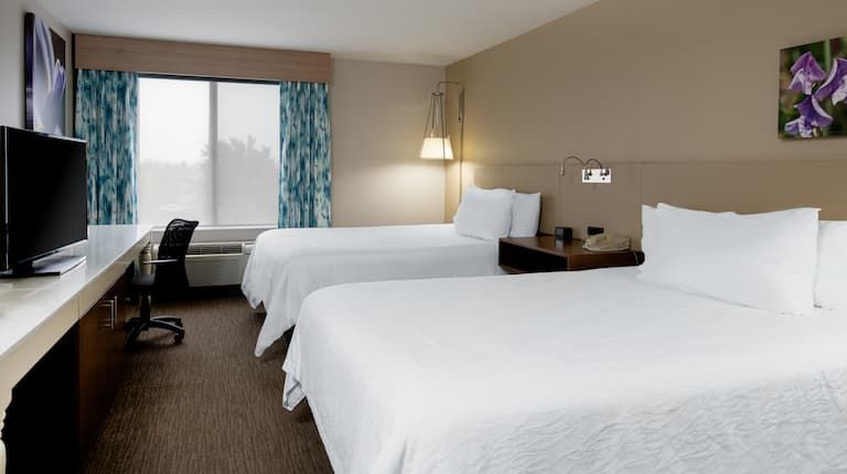 A hotel room with two beds , a desk and a television.