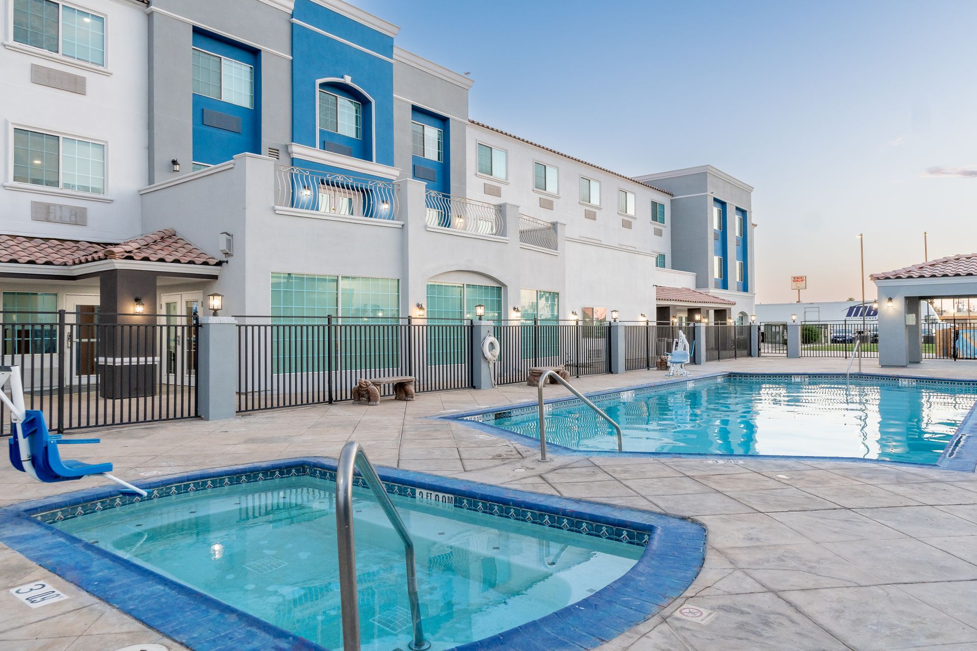 A hotel with a swimming pool and a hot tub in front of it.