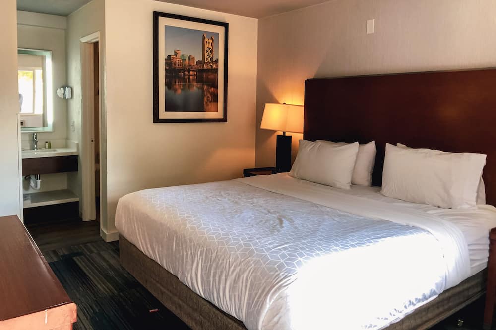 View of the hotel white bed with decorative frame on wall and lamp