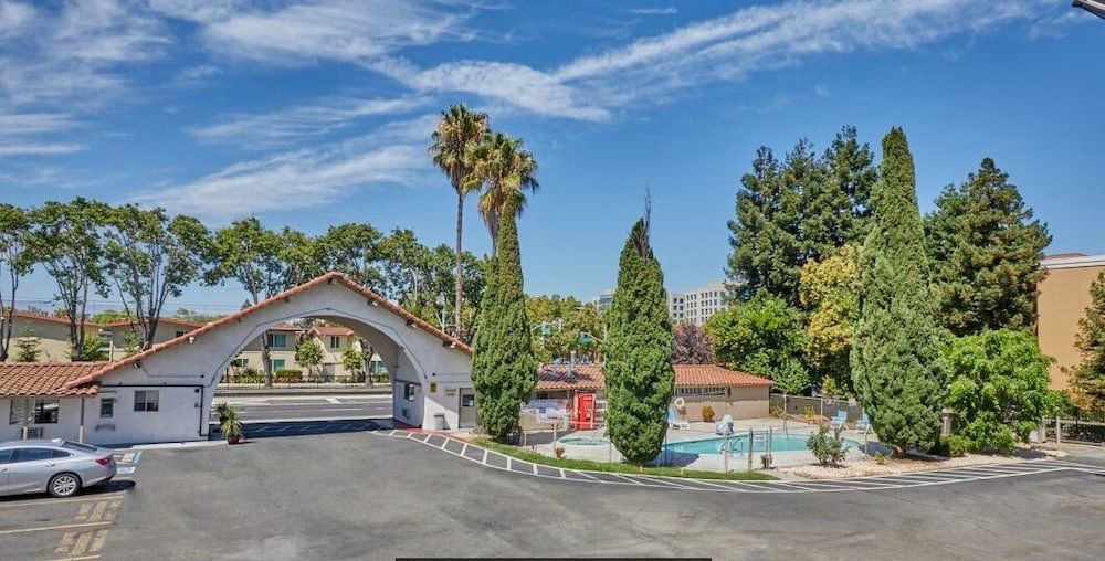 A car is parked in front of a building with a pool in the background.