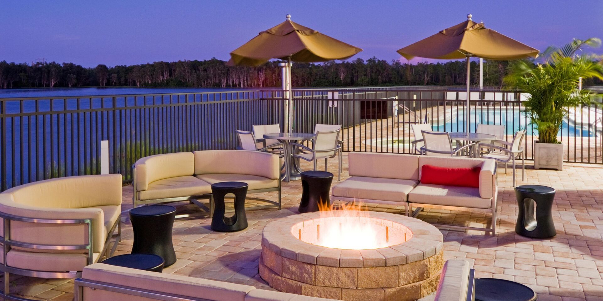 view to the outdoor lounge area with a bonfire and beige couches