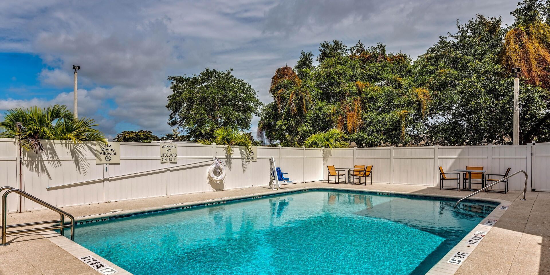 view of the hotel pool area surrounding by large green trees