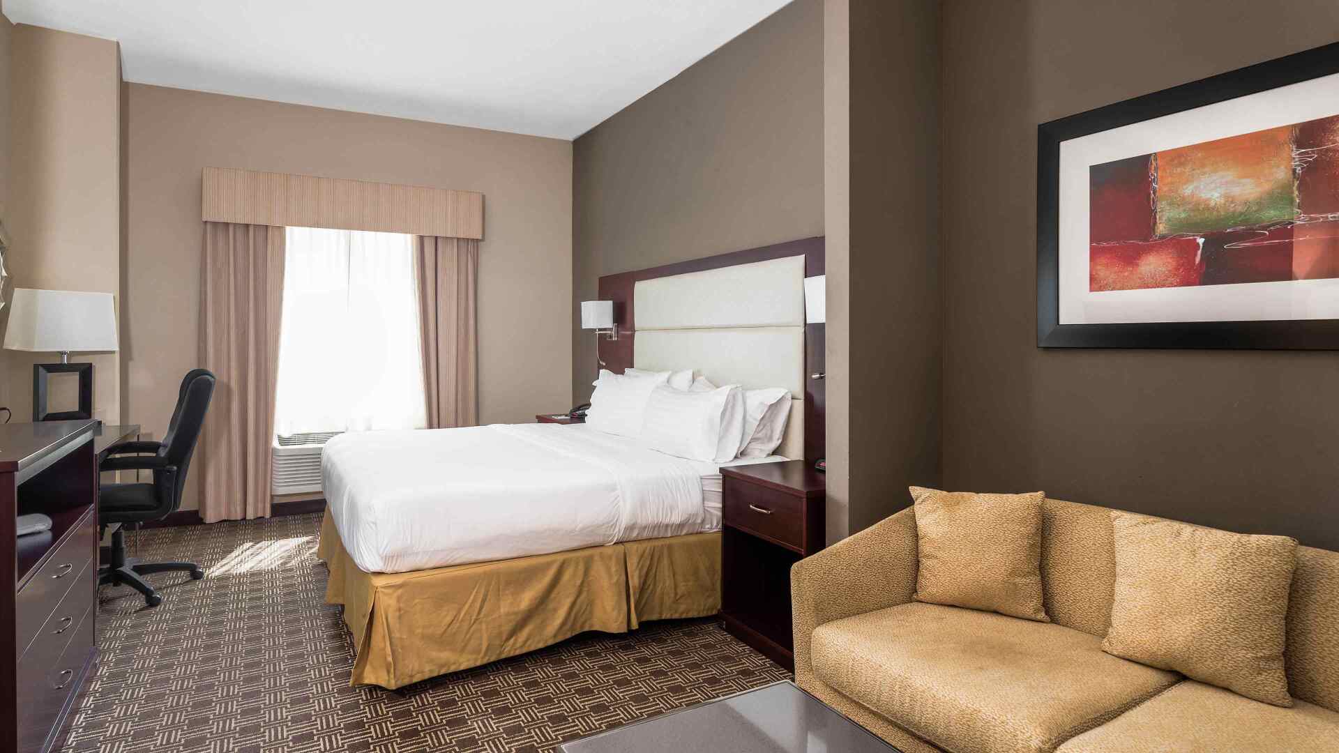 view to the hotel bed with a brown couch next to the bed