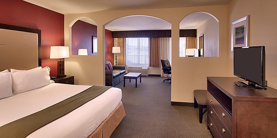 view to the hotel bed, brown cabinet and television