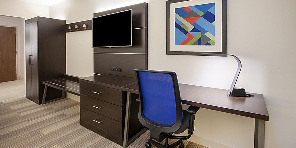 hotel room work area with desk, chair, and television