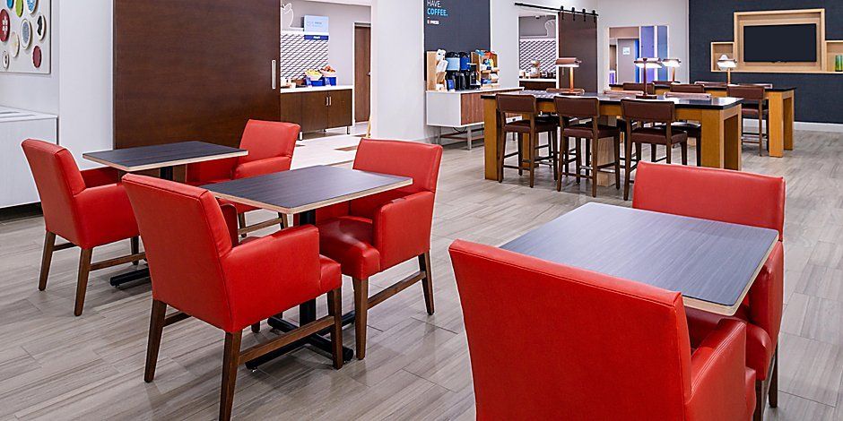 hotel breakfast eating area with tables and bright red chairs