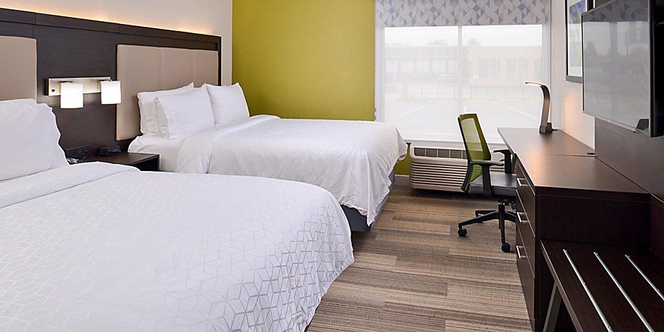 view to the two hotel beds and chair with a green wall