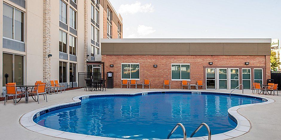 view to the hotel pool with multiple tables and orange chairs surrounding pool