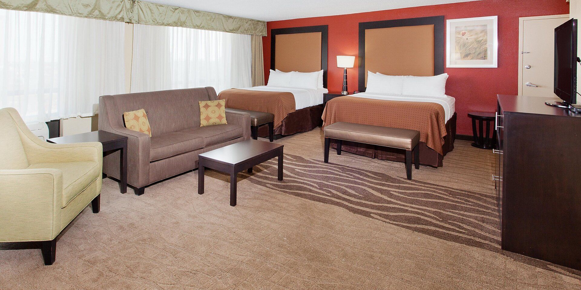 view to two hotel beds with a large brown couch and a coffee table