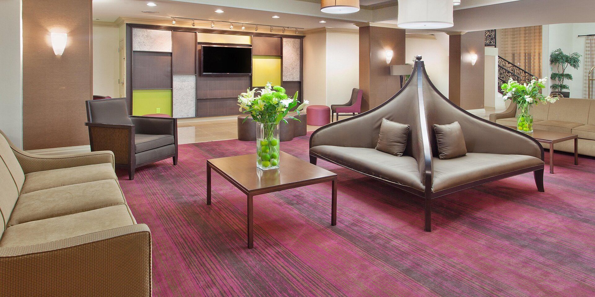 view of the hotel lobby with couches, red carpet, and flowers on top of a coffee table