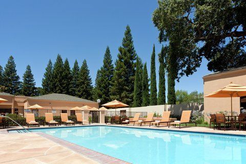 A large swimming pool surrounded by chairs and umbrellas