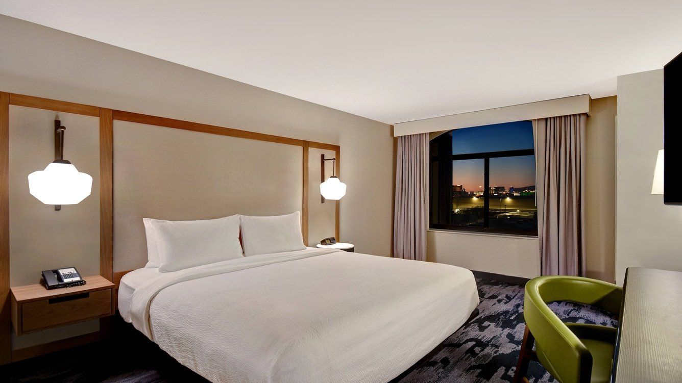 view to the comfortable hotel bed with a decorative lamp