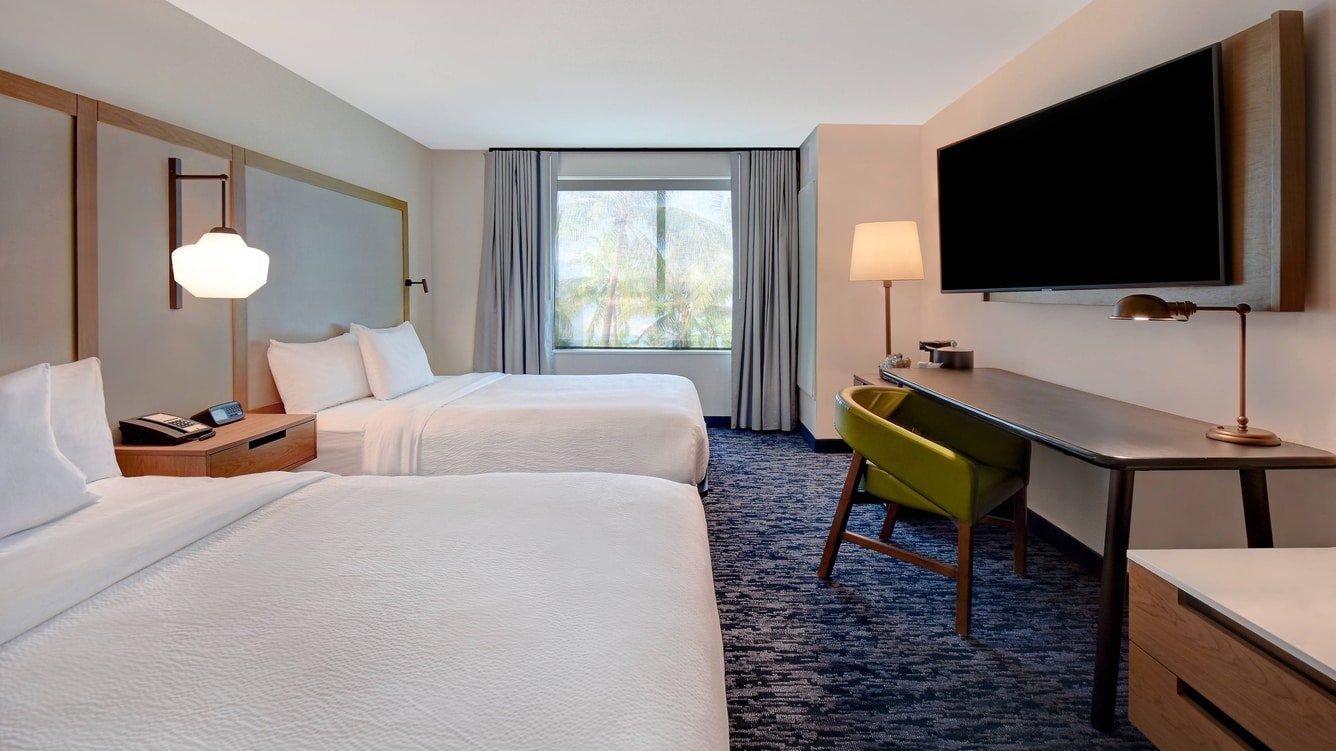 two large white hotel beds with a view to the window