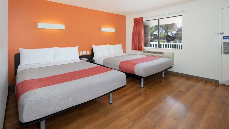 View to the two hotel bed with wood floor and decorative light on wall