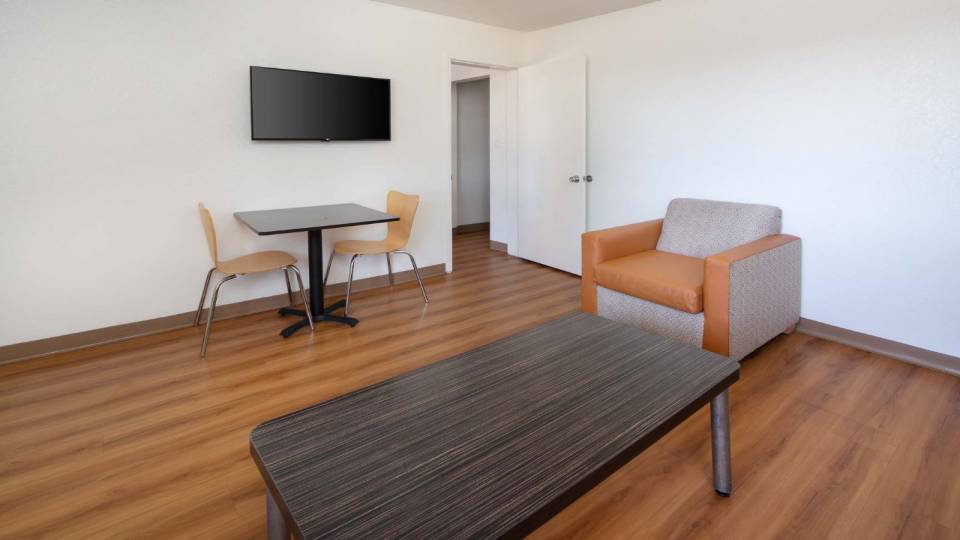 View to the hotel living room area of a coffee table, table, two chairs, and a couch