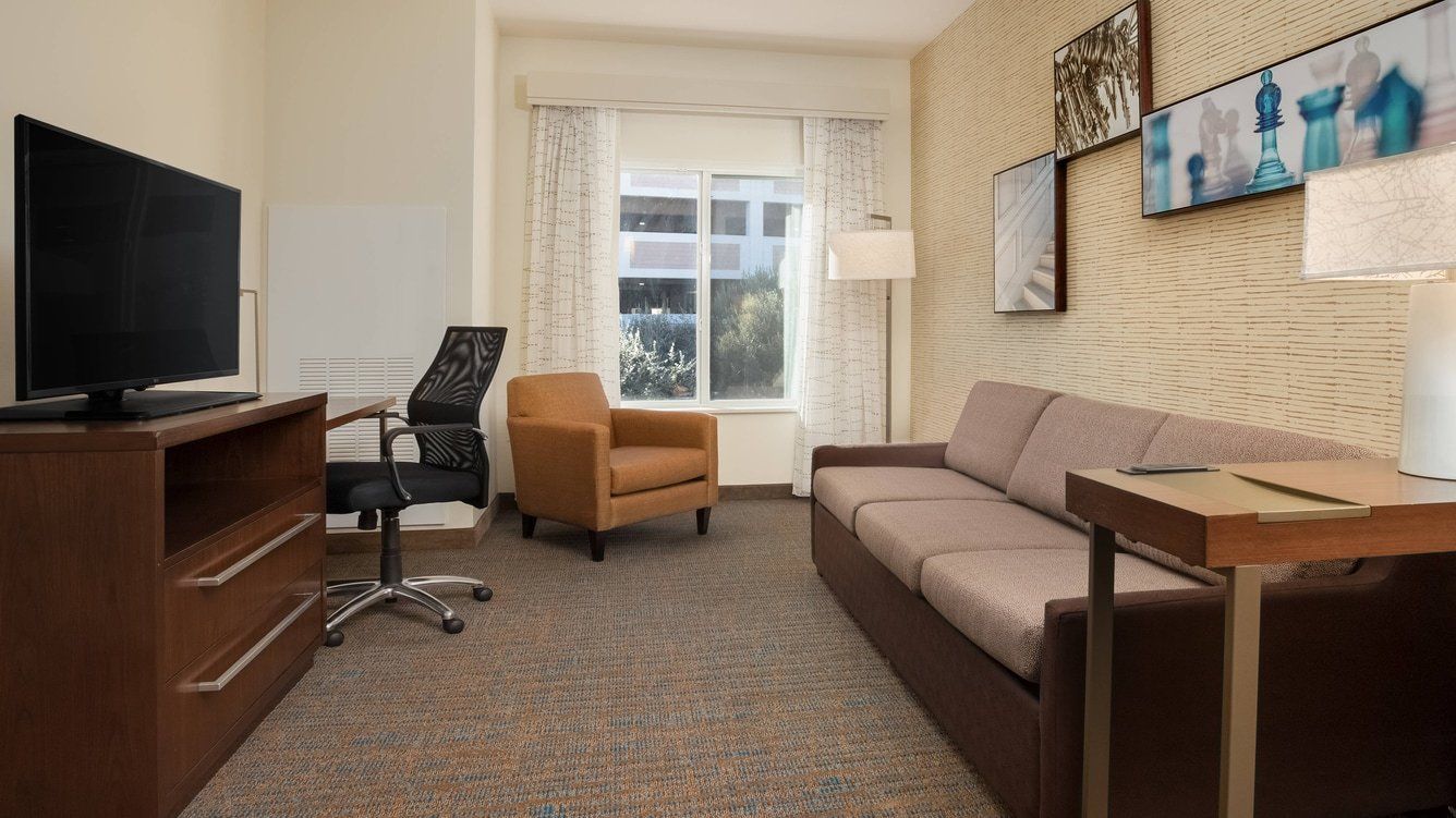 view to the hotel living room area with a large brown couch