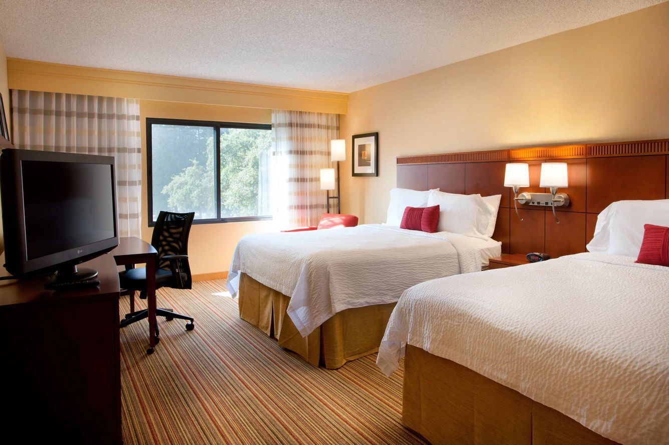 A hotel room with two beds and a flat screen tv