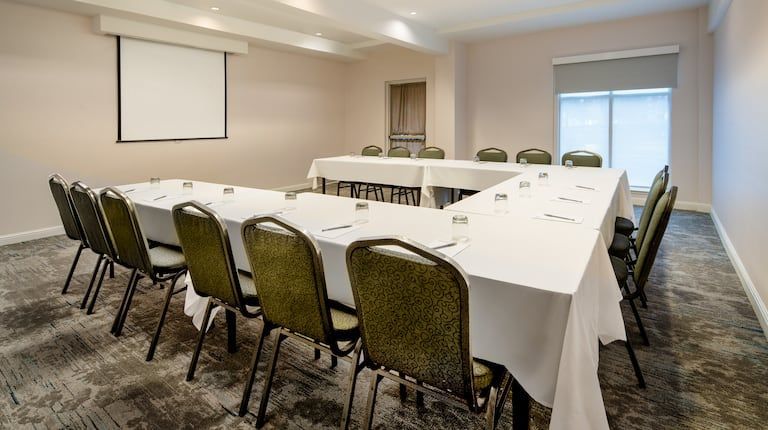 A conference room with a long table and chairs and a projector screen.