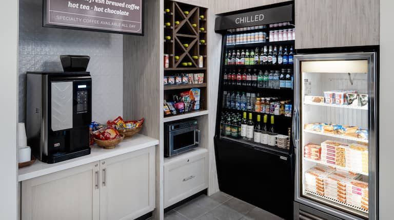 A room with a refrigerator , a coffee maker , a microwave , and a wine rack.