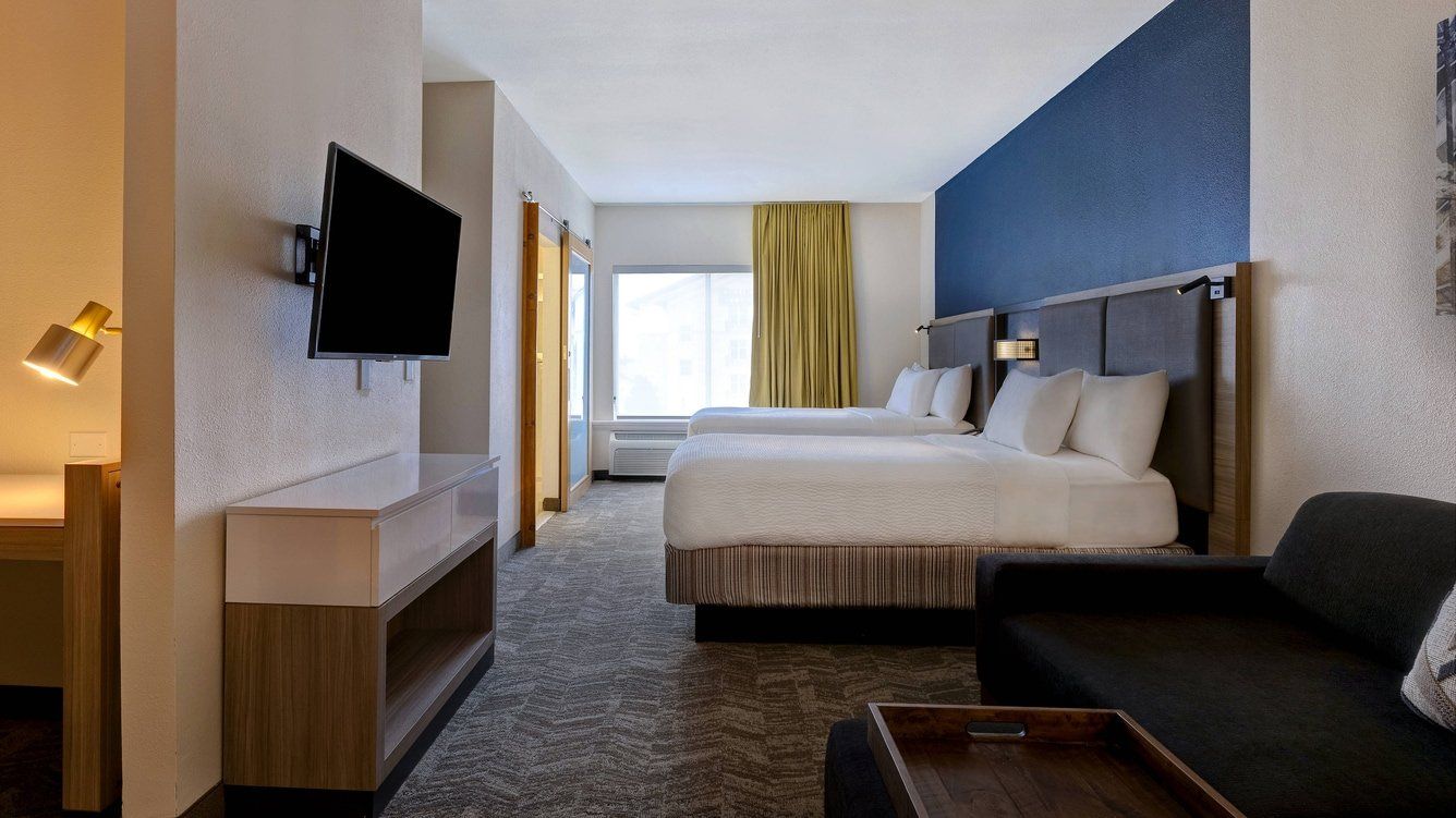 view of the entire hotel room with two large beds facing the television