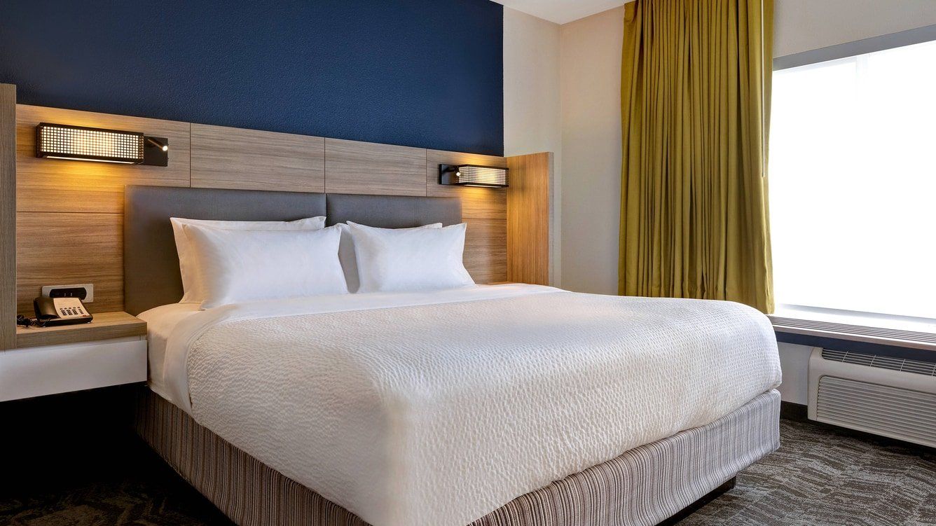 close up of the hotel bed with a lamp and green window curtains