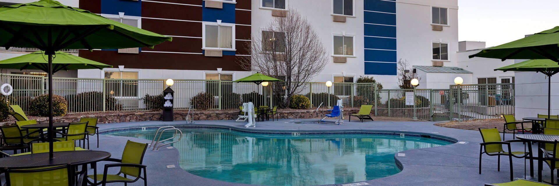 view of the hotel pool with tables and green chairs surrounding the pool