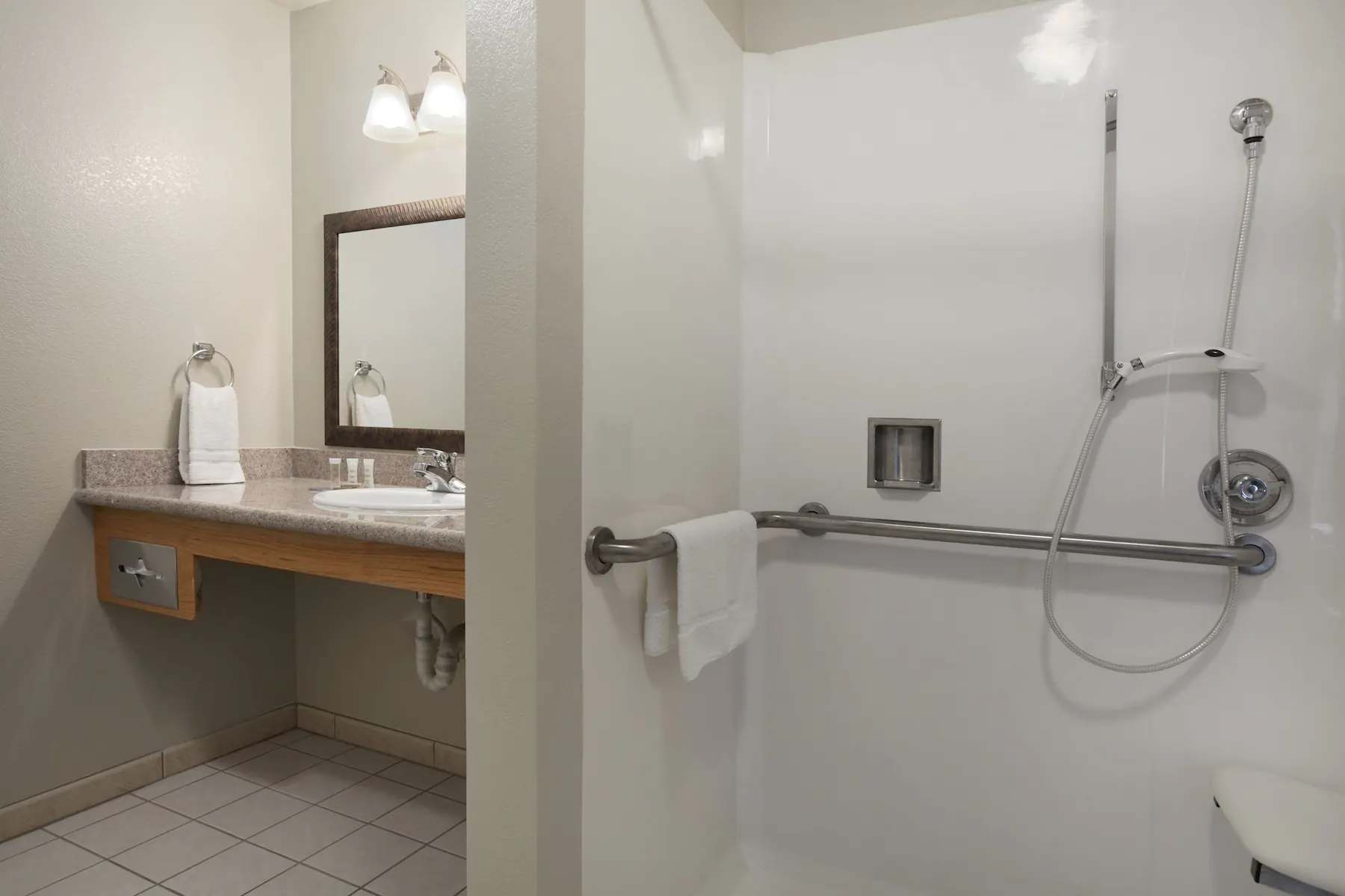 Hotel bathroom with a large shower and a sink as well as a mirror